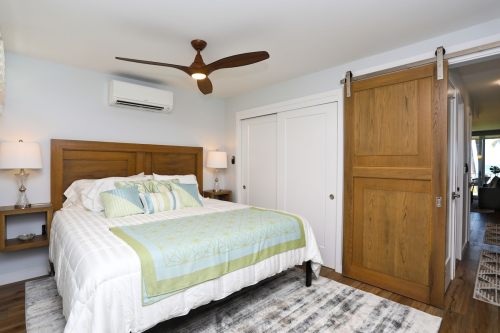 Cozy bedroom featuring a wooden bed, ceiling fan, and sliding door, with soft blue and green decor.