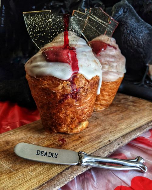 Two dessert cupcakes with glossy icing and a red sauce, displayed on a wooden board with a knife labeled "DEADLY."