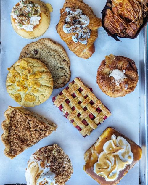 A variety of baked goods including cookies, pastries, and pie, arranged on a tray with a white background.