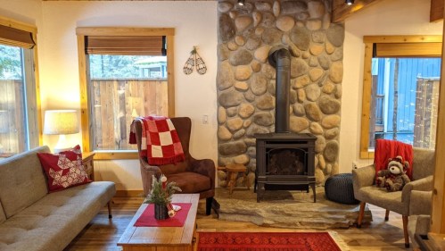 Cozy living room with a stone fireplace, comfortable seating, and festive decor, creating a warm atmosphere.