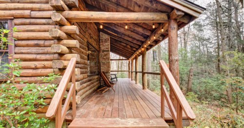 a set of wood stairs leads to the front porch of a log cabin airbnb rental in ct