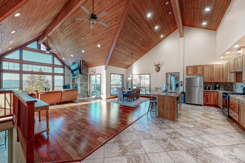 Spacious, modern living area with high wooden ceilings, large windows, and a cozy kitchen in a mountain home.