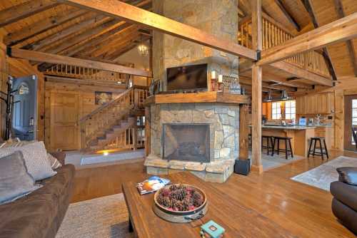 Cozy wooden cabin interior featuring a stone fireplace, open staircase, and a warm living area with rustic decor.