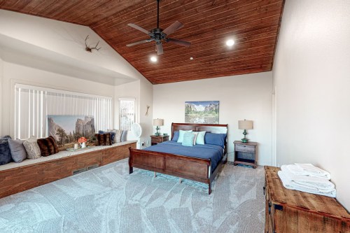 Spacious bedroom with a wooden ceiling, large bed, and cozy seating area by the window.