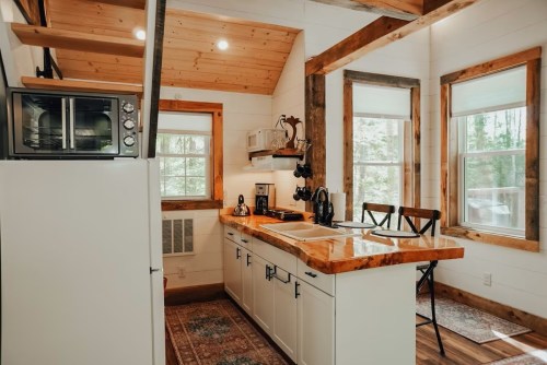 Cozy kitchen with wooden accents, a microwave, and large windows, featuring a central island and dining area.
