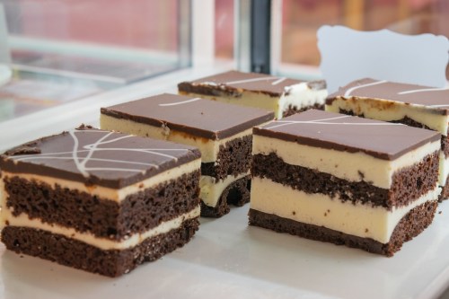 A display of layered chocolate and cream desserts, featuring a glossy chocolate topping and decorative white lines.