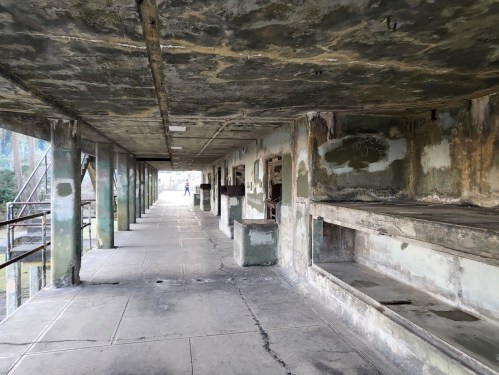 Abandoned corridor with peeling walls and empty spaces, showing signs of decay and neglect.