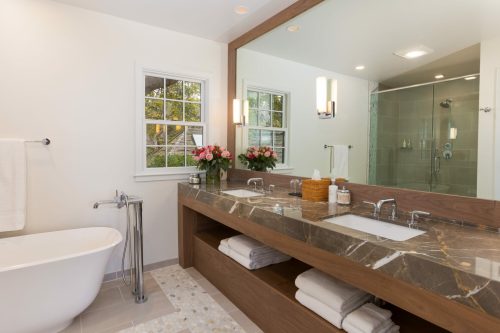 Modern bathroom featuring a freestanding tub, double sink vanity, and a large mirror with natural light.