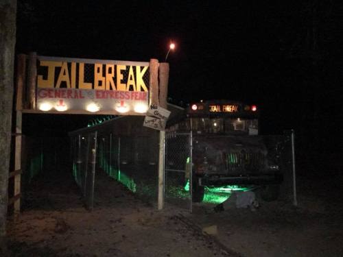 A dimly lit scene featuring an old bus behind a fence, with a sign reading "TAIL BREAK" illuminated at night.