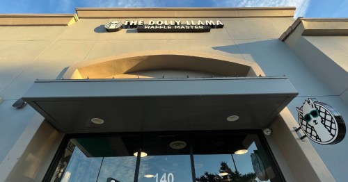 Exterior view of The Dolly Llama Waffle Master, featuring a sign and a whimsical waffle cone logo.