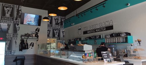 Interior of The Dolly Llama, featuring a modern design, waffle station, and a menu display on the wall.