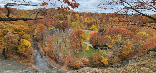 A scenic view of a colorful autumn landscape with trees in vibrant fall colors and a winding creek below.