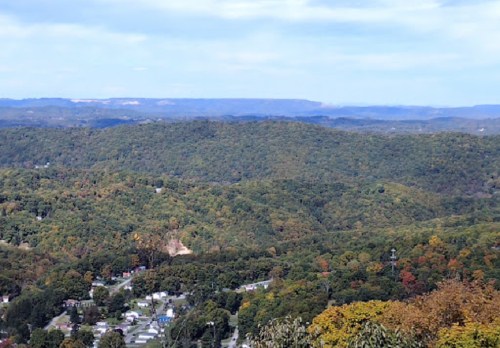 A panoramic view of rolling hills covered in autumn foliage under a clear blue sky.