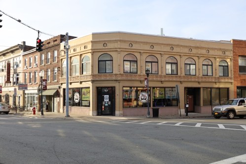 A corner building with large windows and decorative architecture, located at an intersection with traffic lights.