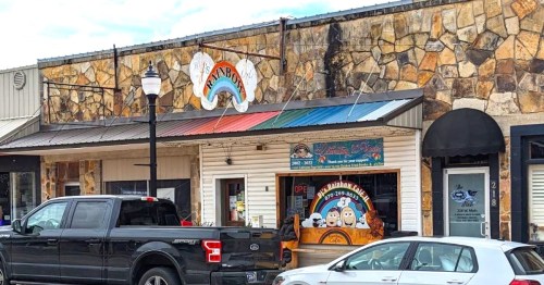 A colorful storefront with a rainbow awning, featuring a sign that says "Open" and a playful design.