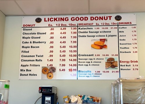 Menu board displaying various donuts, breakfast items, and drinks with prices listed for each item.