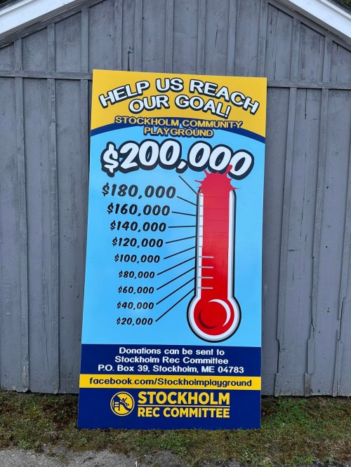Sign displaying a fundraising thermometer for a community playground, aiming to raise $200,000 in Stockholm, ME.