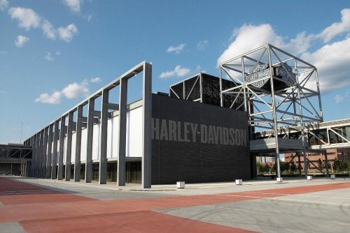Exterior view of the Harley-Davidson building with modern architecture and a large logo sign against a blue sky.