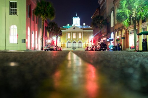 A nighttime street view with palm trees, illuminated buildings, and a central historic structure under a clear sky.