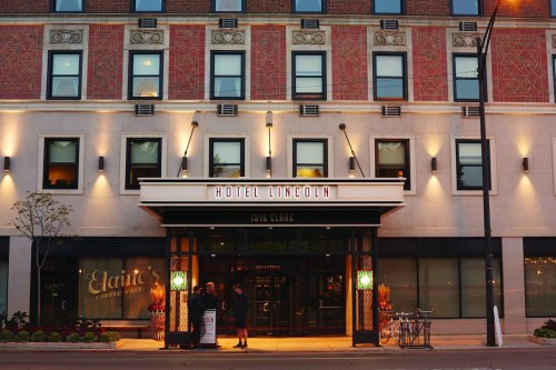 Exterior of Hotel Lincoln, featuring a stylish entrance with lights and a bicycle parked outside.