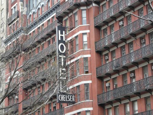 Historic Hotel Chelsea building with a prominent black sign, featuring red brick and decorative balconies.