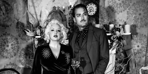 A vintage-inspired black and white photo of a glamorous couple posing together, surrounded by retro decor.