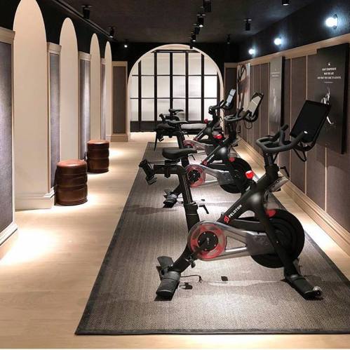 A modern fitness studio featuring stationary bikes, wooden stools, and stylish archways in a well-lit space.