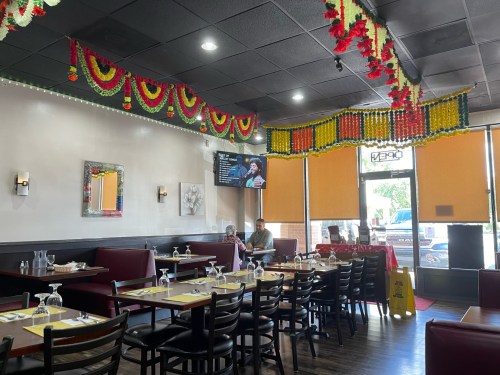 Interior of a restaurant with festive decorations, tables set for dining, and a TV displaying a performance.