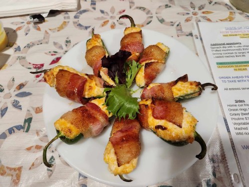 A plate of bacon-wrapped jalapeño poppers filled with cheese, arranged in a circular pattern with greens in the center.