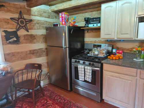 A rustic kitchen with a stainless steel fridge, stove, and wooden cabinets, featuring a cozy dining area and colorful decor.