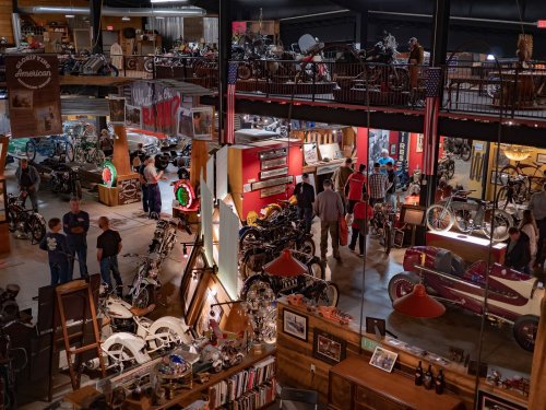 A bustling museum filled with vintage bicycles and memorabilia, with visitors exploring the exhibits.