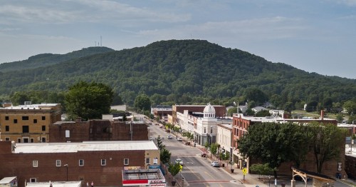 A scenic view of a small town with a mountain in the background, featuring buildings lining a quiet street.