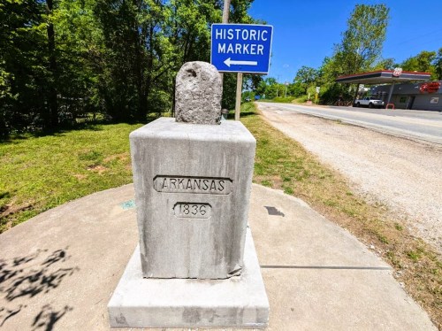 Historic marker for Arkansas, featuring a stone monument with the year 1836, set in a green landscape.