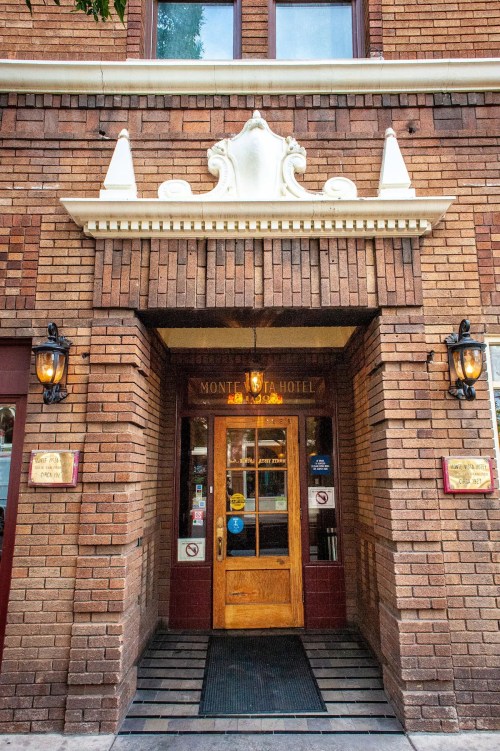 Entrance of the Monte Vista Hotel, featuring a wooden door and decorative brickwork with vintage light fixtures.
