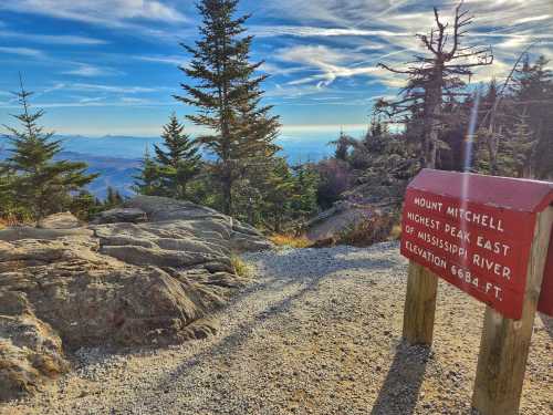 A scenic view from Mount Mitchell, with a sign indicating its elevation and status as the highest peak east of the Mississippi.