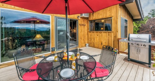 a patio table set with dishes and glassware outside a cabin in new mexico