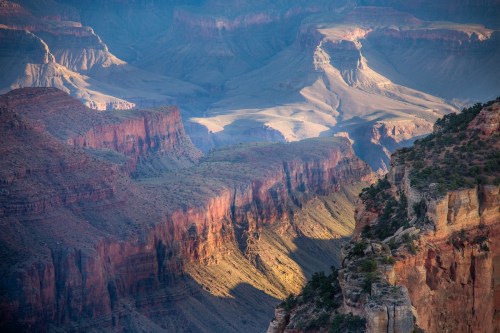 A panoramic view of the Grand Canyon, showcasing layered rock formations and dramatic shadows in the landscape.