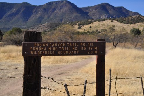 Trail signpost indicating Brown Canyon Trail No. 115, Pomona Mine Trail No. 116, and Wilderness Boundary 2.0 miles.