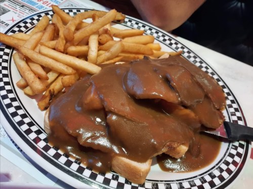 A plate of fries alongside sliced bread topped with gravy, creating a hearty meal.