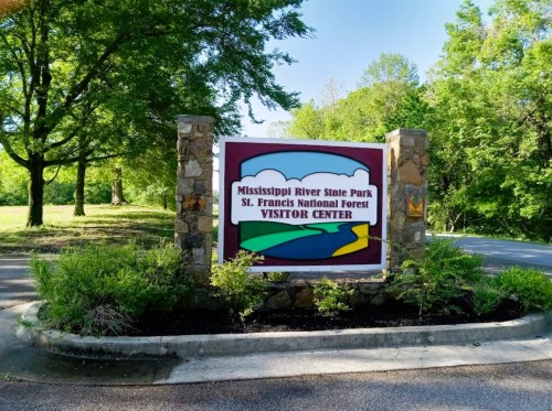 Sign for Mississippi River State Park Visitor Center, surrounded by greenery and trees.