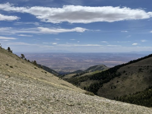 A panoramic view of rolling hills and valleys under a blue sky with scattered clouds.