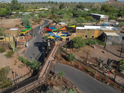Aerial view of a colorful outdoor area with pathways, buildings, and greenery in a desert landscape.