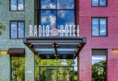Entrance of Radio Hotel featuring colorful brick facade and large sign under a clear blue sky.
