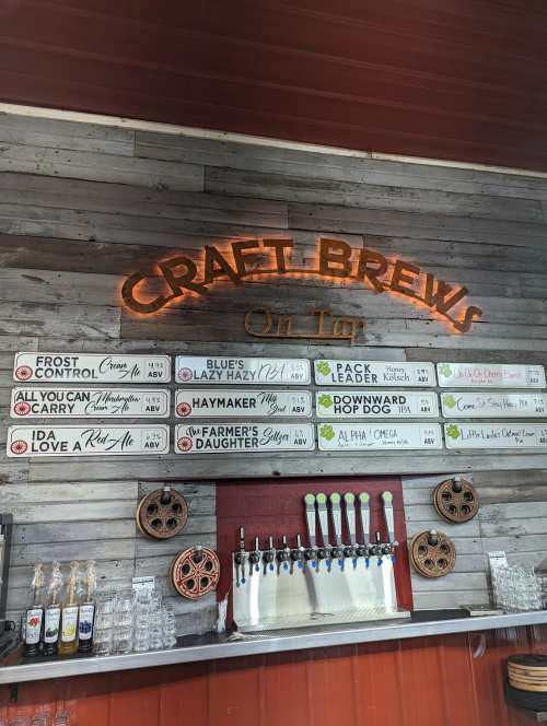 A rustic bar display featuring a sign that reads "Craft Brews" and a menu of various beer options on a wooden wall.