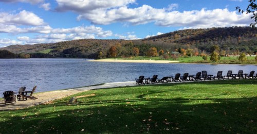chairs line the shoreline of the lake at rocky gap stte park in maryland in the fall