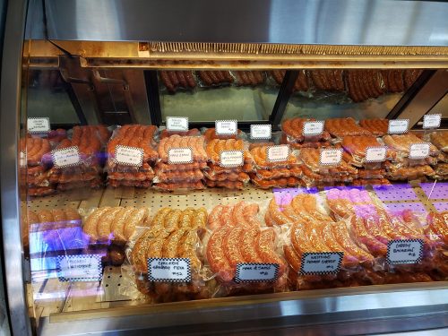 A display case filled with various types of sausages, neatly arranged and labeled.