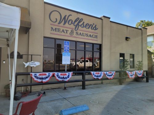 Exterior of Wolfsen's Meat & Sausage with patriotic bunting and a sign indicating accessible parking.