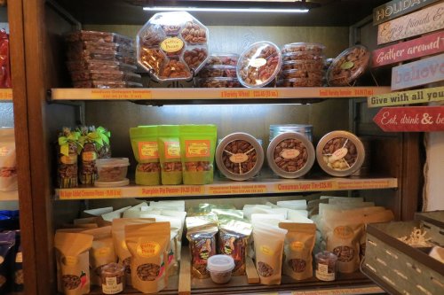 A display shelf filled with various packaged snacks, including nuts, cookies, and candies in clear containers and bags.