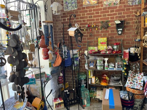 A cozy shop interior filled with various garden and home decor items, including bird feeders and gardening supplies.