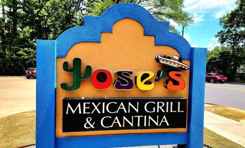 Colorful sign for Yoser's Mexican Grill & Cantina, featuring a sombrero and vibrant lettering against a blue background.